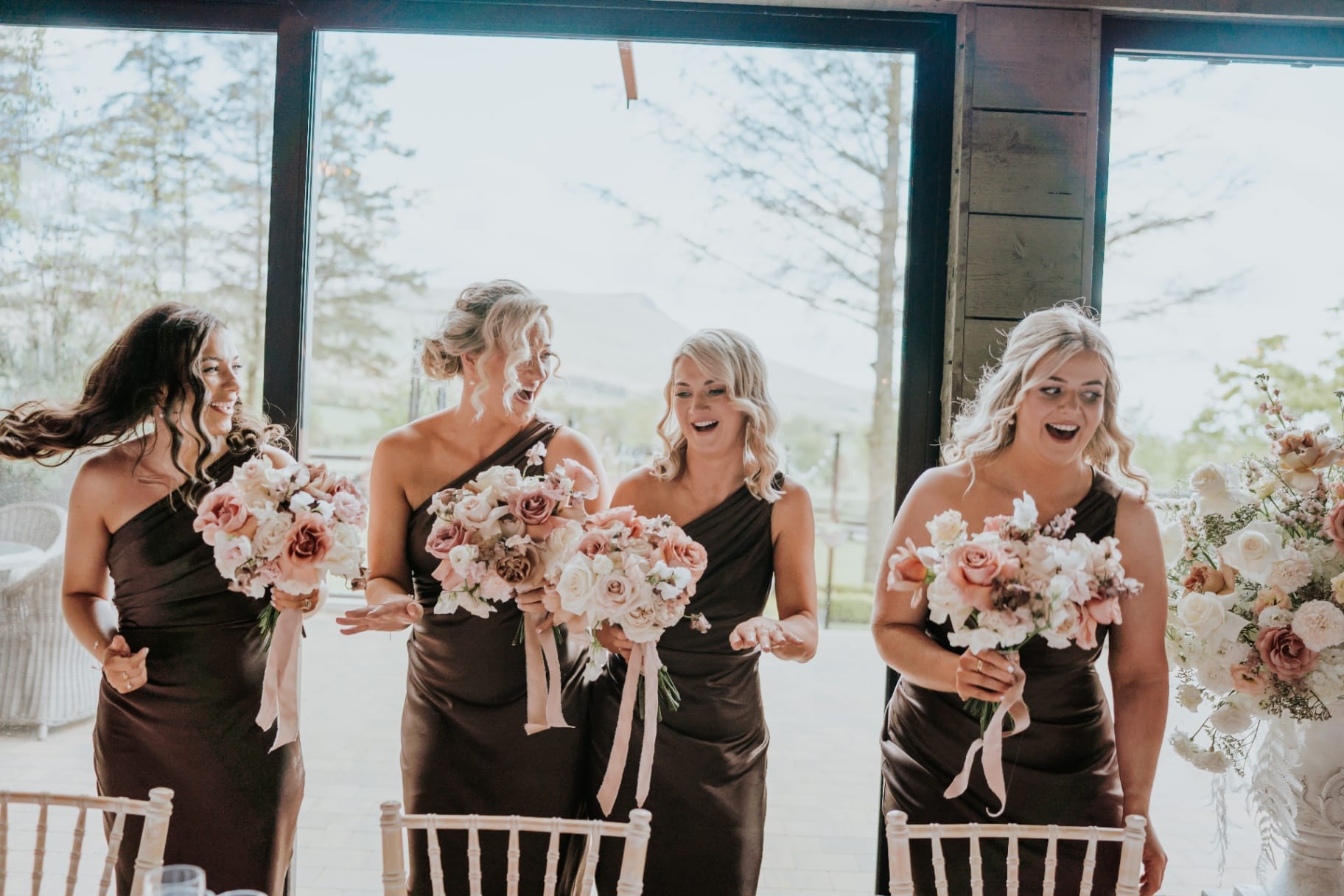 Bridesmaids reacting with bouquets during a wedding moment indoors