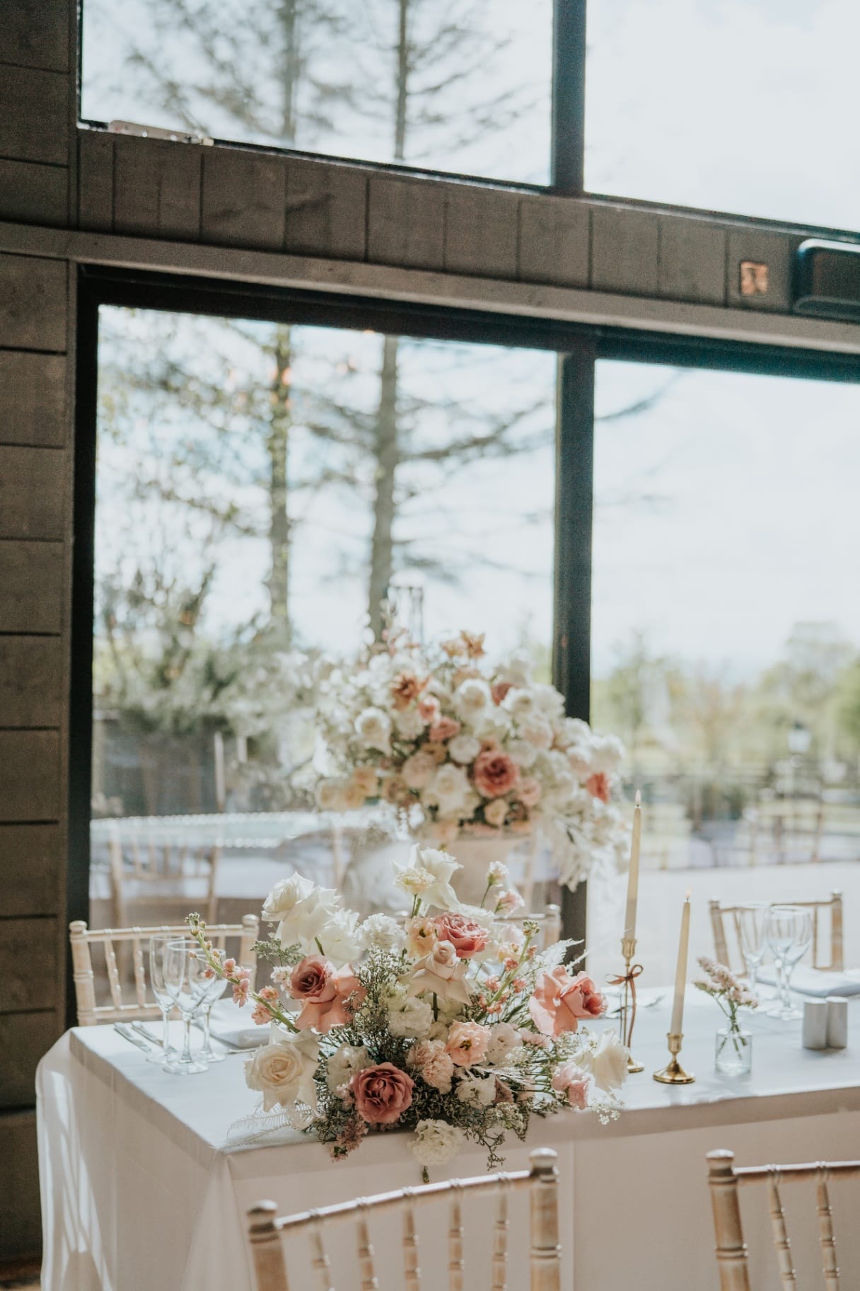 Sweetheart table with blush and white floral arrangements by the window