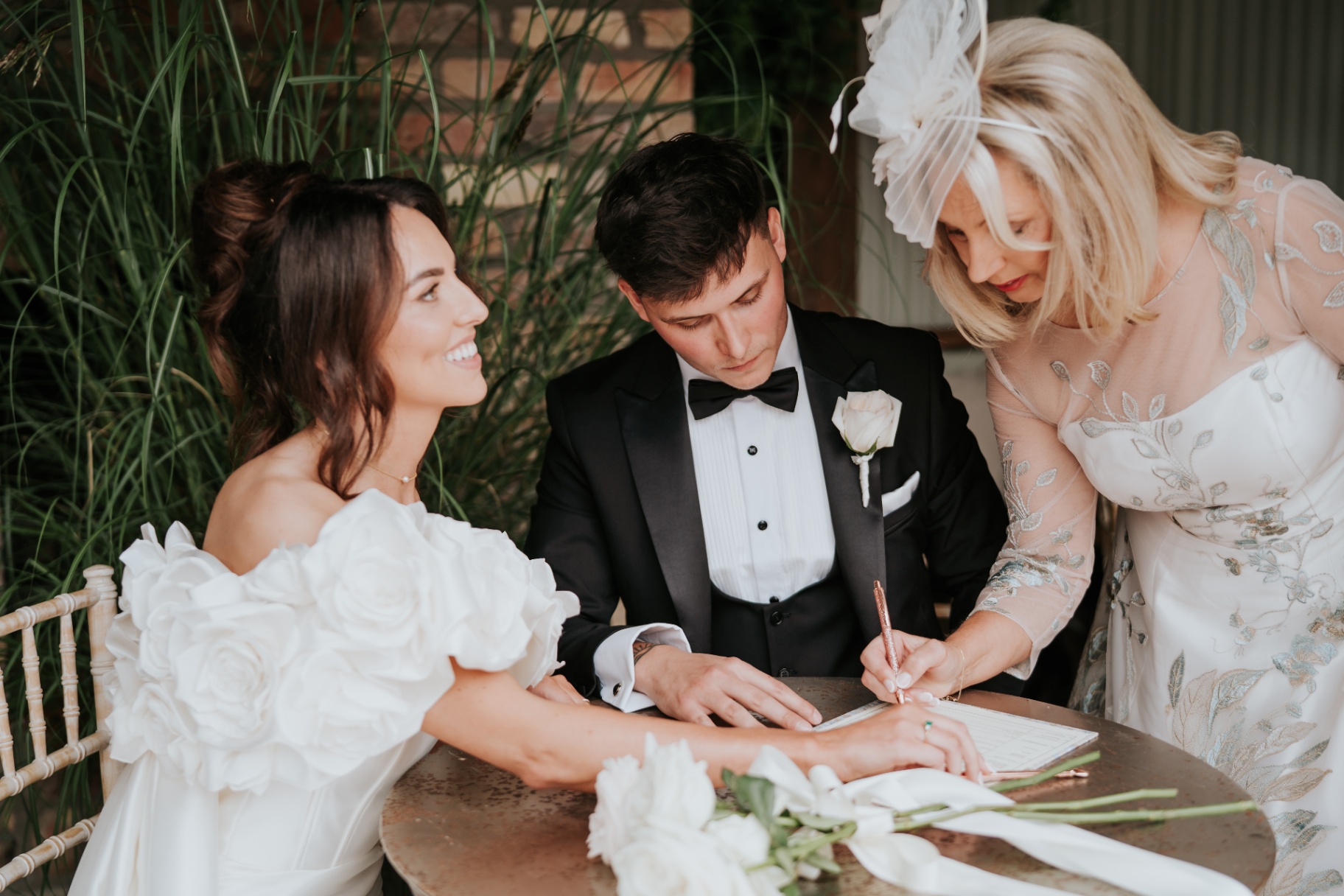 Signing the register with the mother of the bride looking on