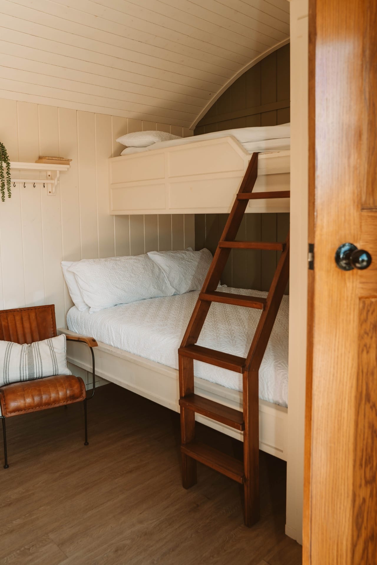 Shepherd's Hut bunk beds with timber ladder and leather chair