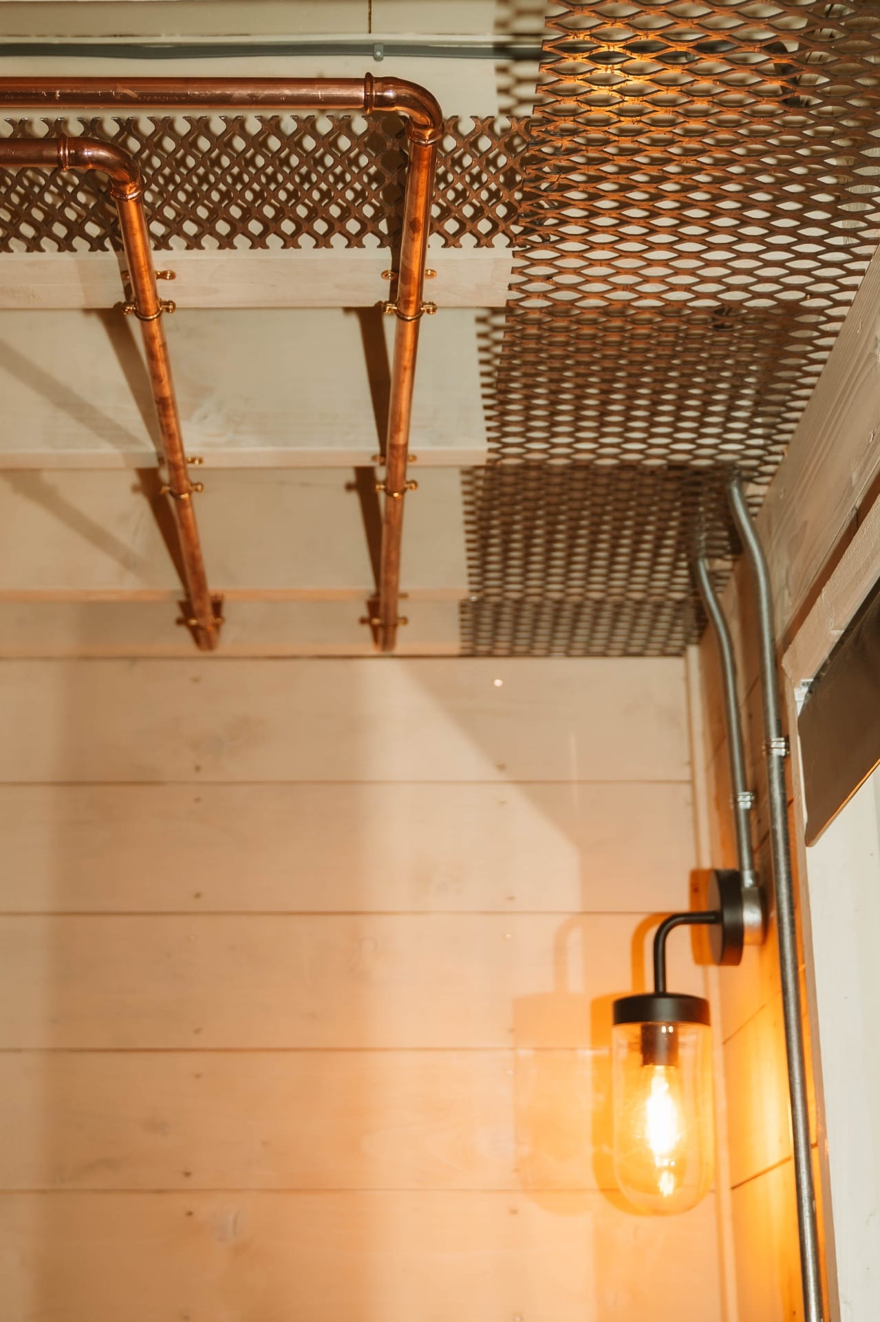 Treehouse Lookout copper plumbing on shiplap wall with mesh ceiling and wall lantern