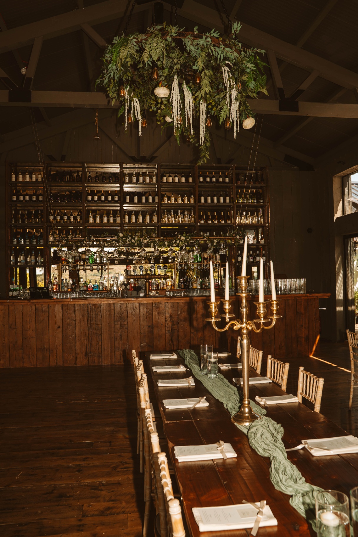 Indoor bar and long dining table dressed for a reception