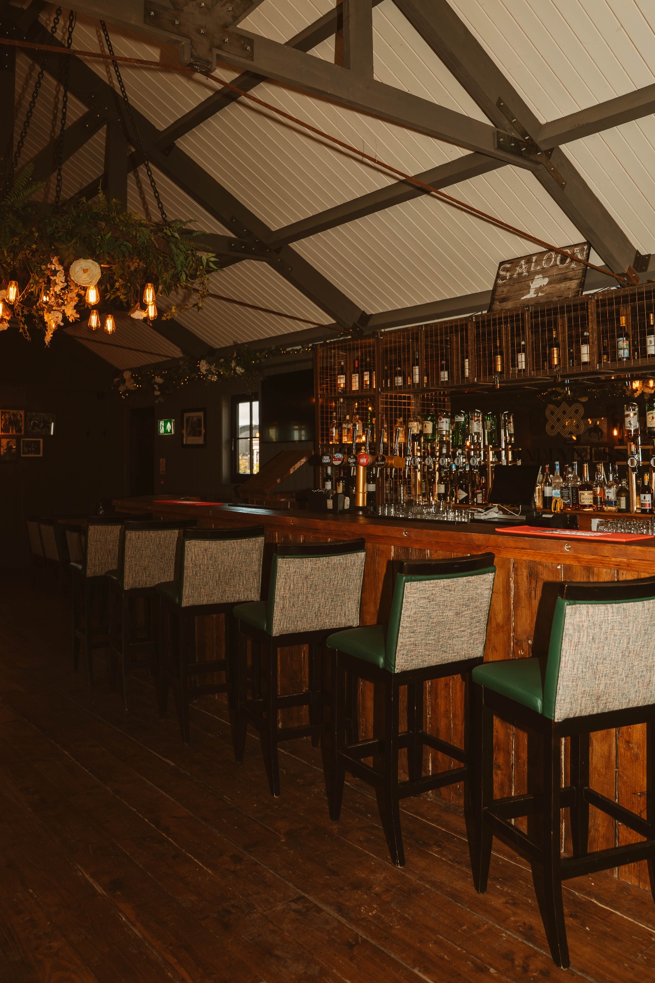 Long view down the Saloon bar with bar stools and floral chandelier