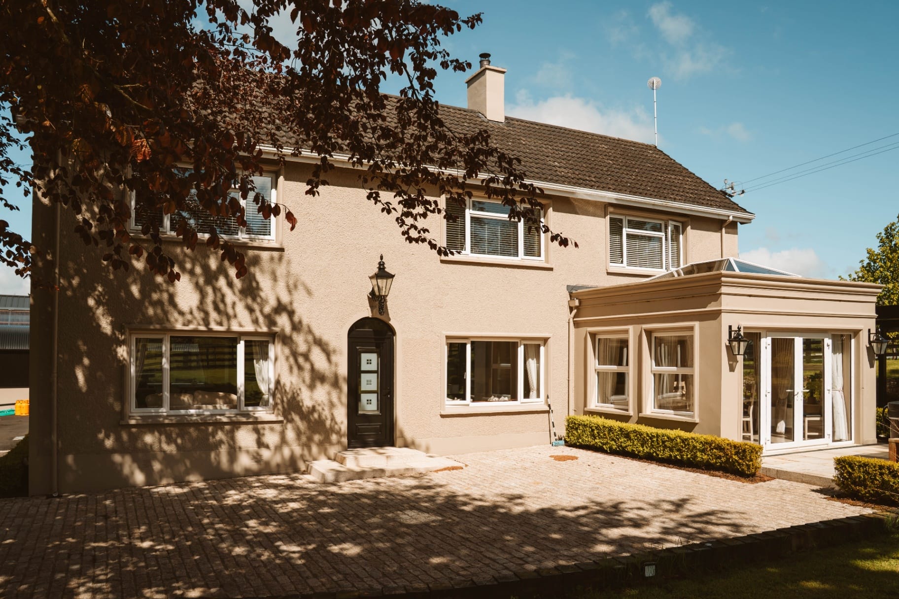 Farmhouse front elevation with conservatory and copper beech
