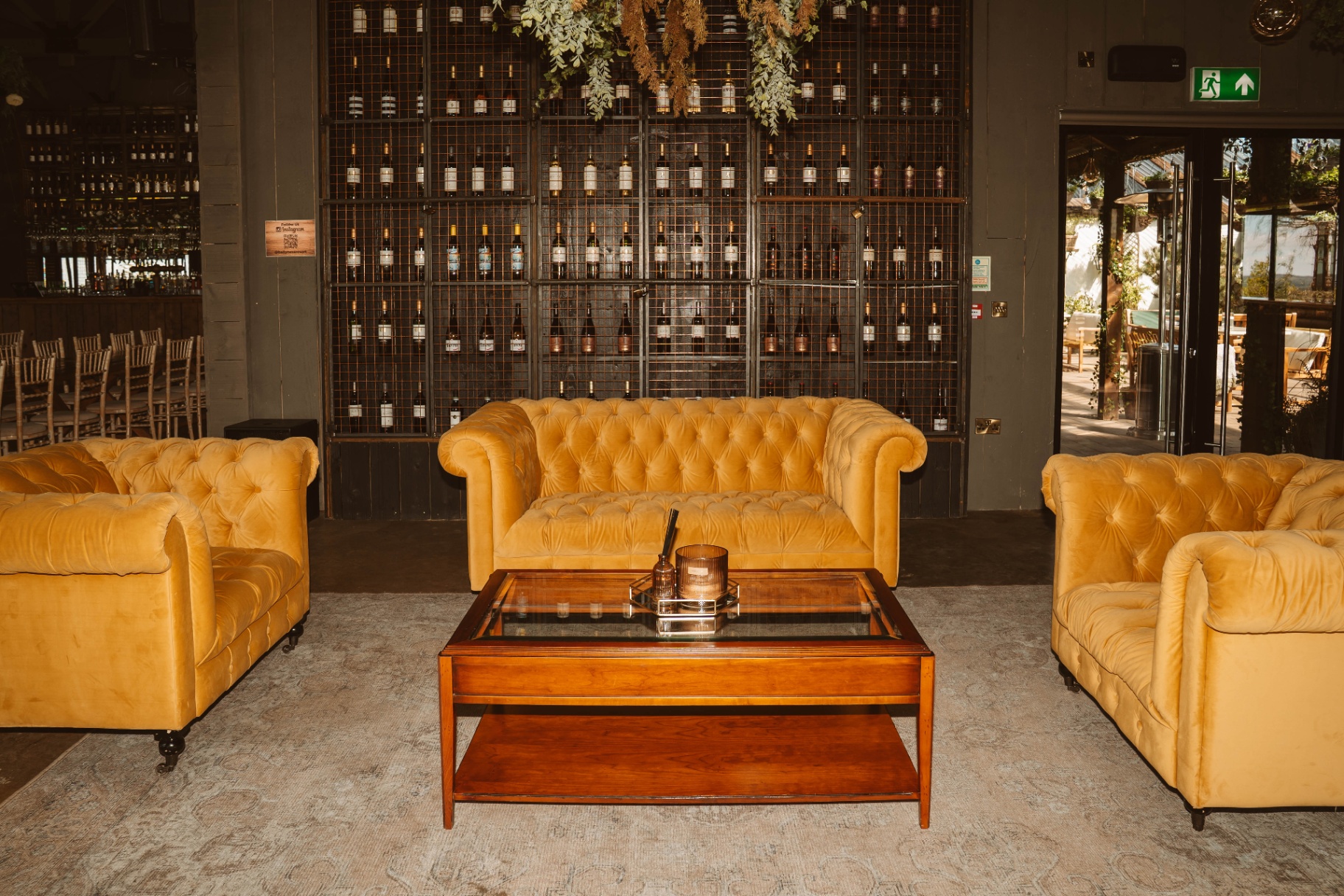 Mustard chesterfield lounge beside the whiskey wall