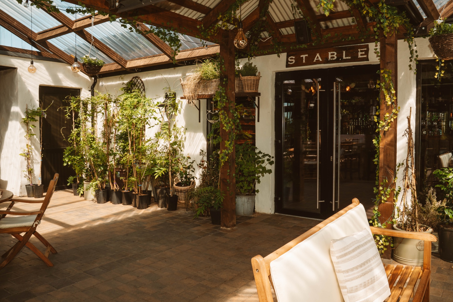 The Stable entrance with double glass doors and ivy-clad pergola
