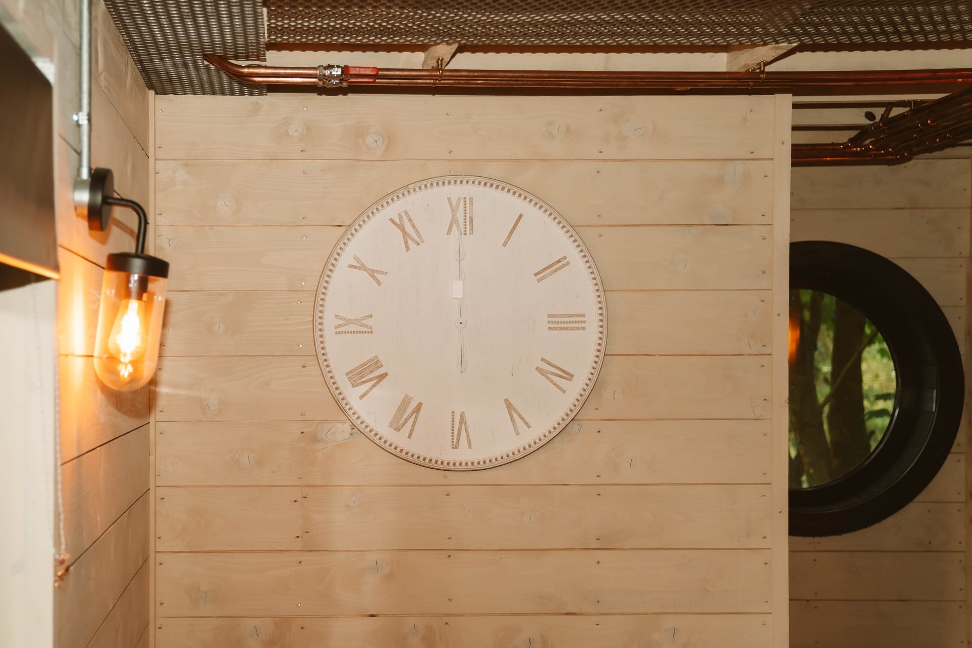 Treehouse Lookout Roman numeral wall clock with copper pipework above