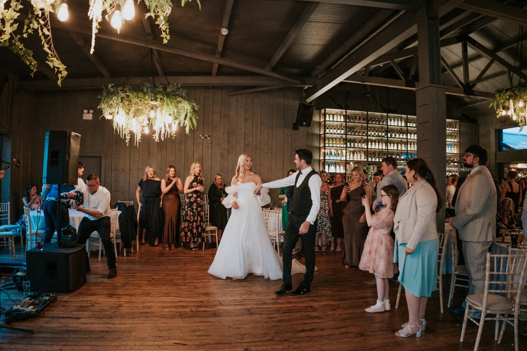 Bride and groom share their first dance on the wooden barn dance floor