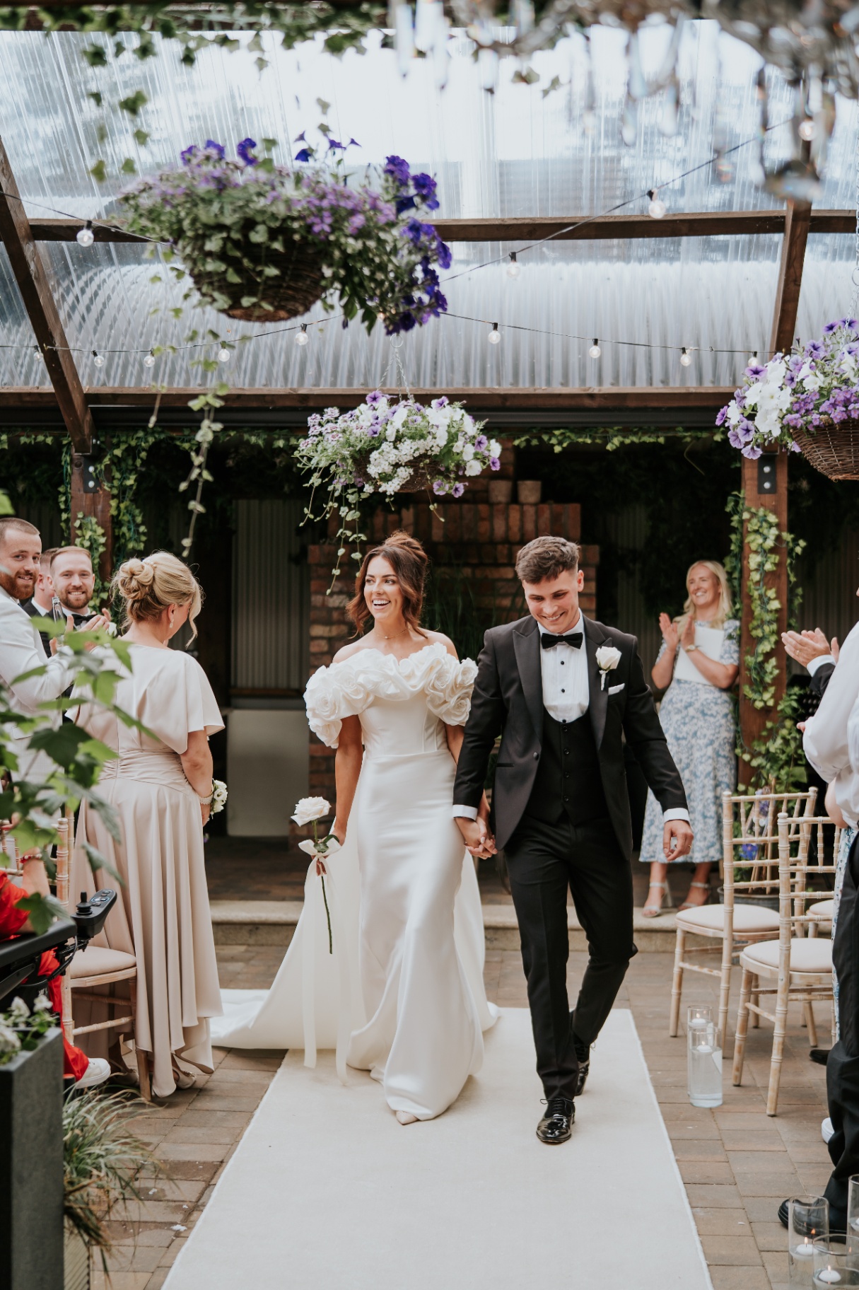 Newlyweds walking hand in hand through cheering guests