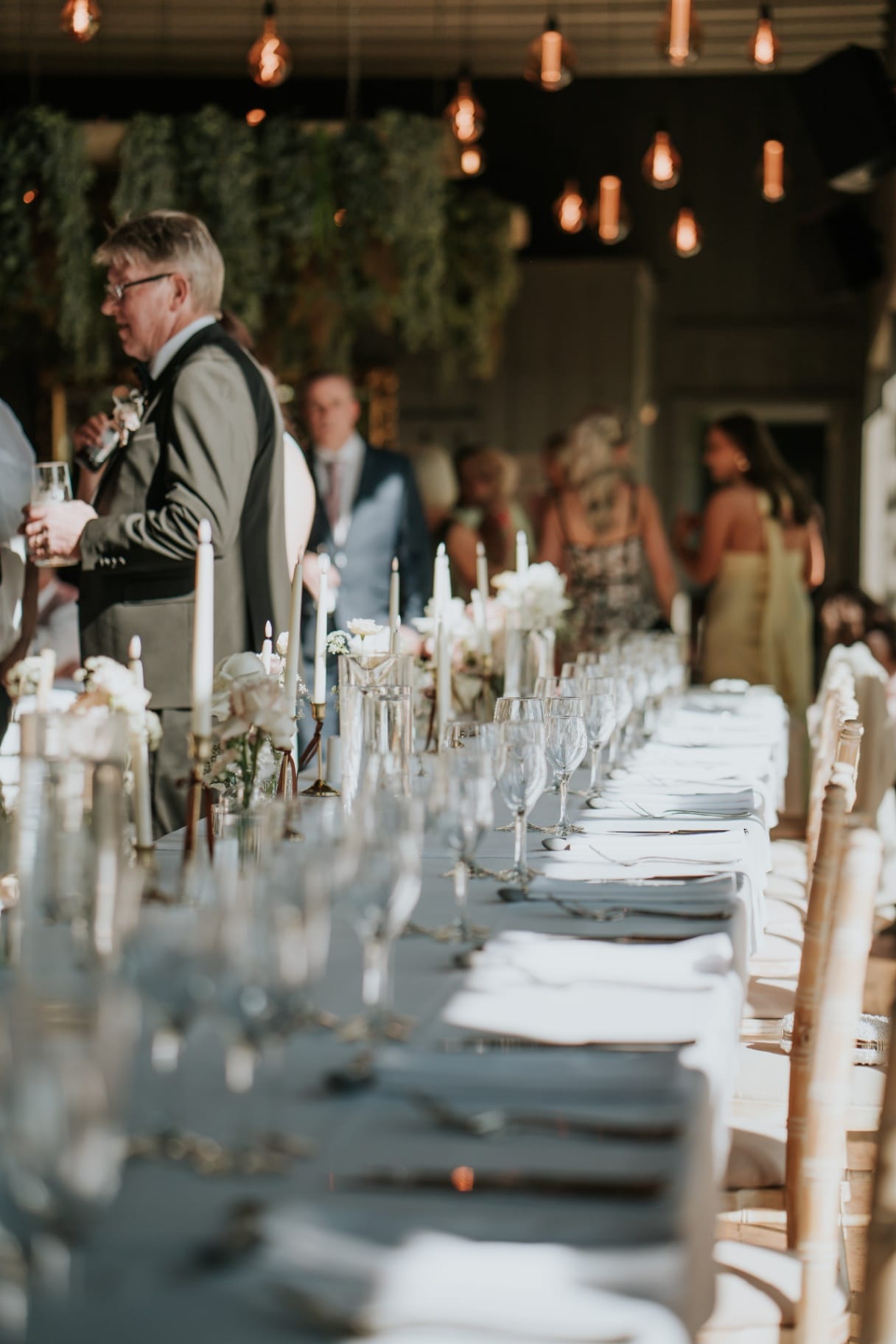 Reception top table with candles and pendant lighting during speeches