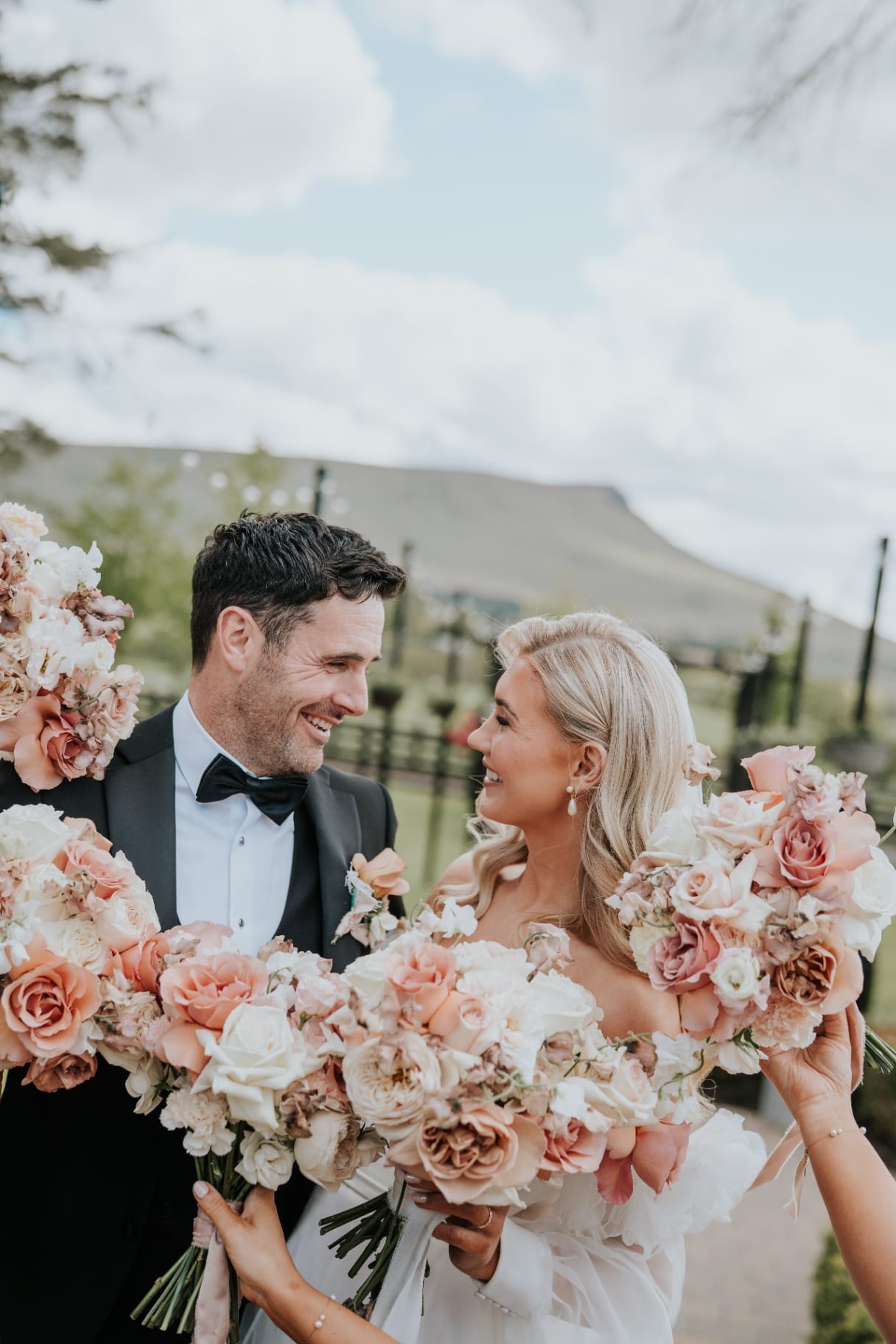 Bride and groom smiling behind bouquets in a close portrait