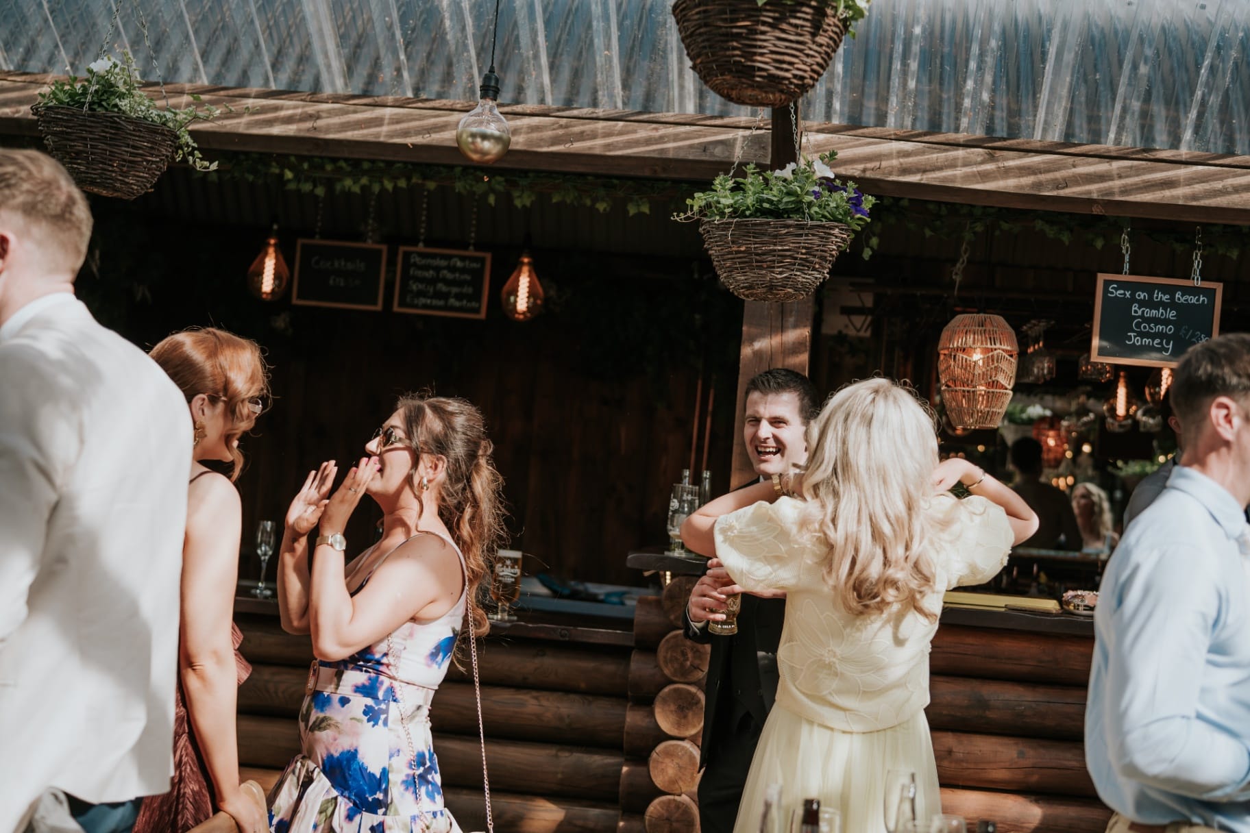 Wedding guests laughing and hugging at the outdoor cocktail bar