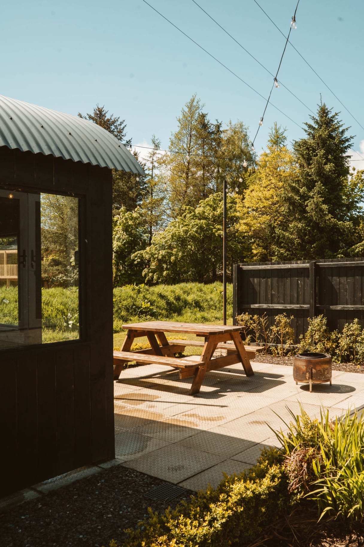 Shepherd's Hut patio with picnic bench and festoon lights