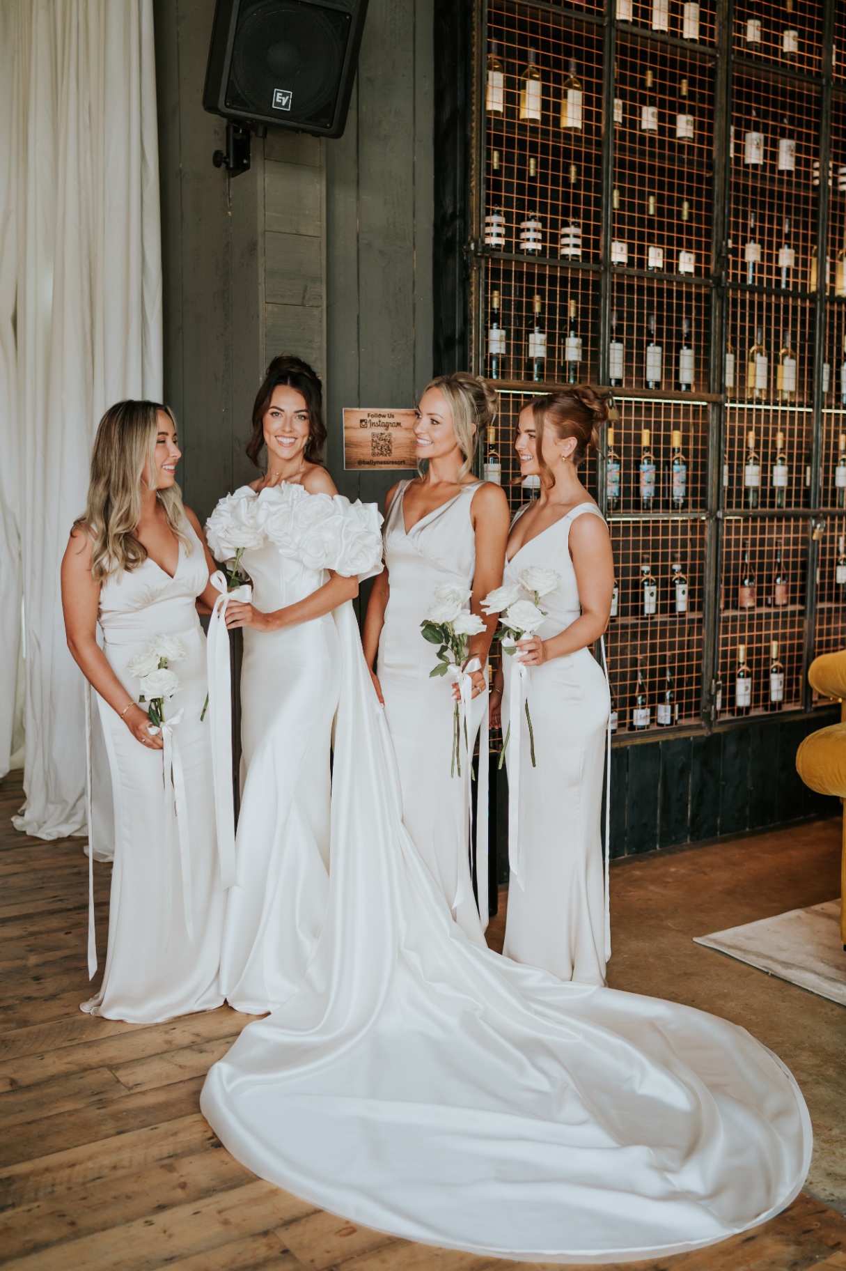 Bride and bridesmaids in front of the wine bottle wall