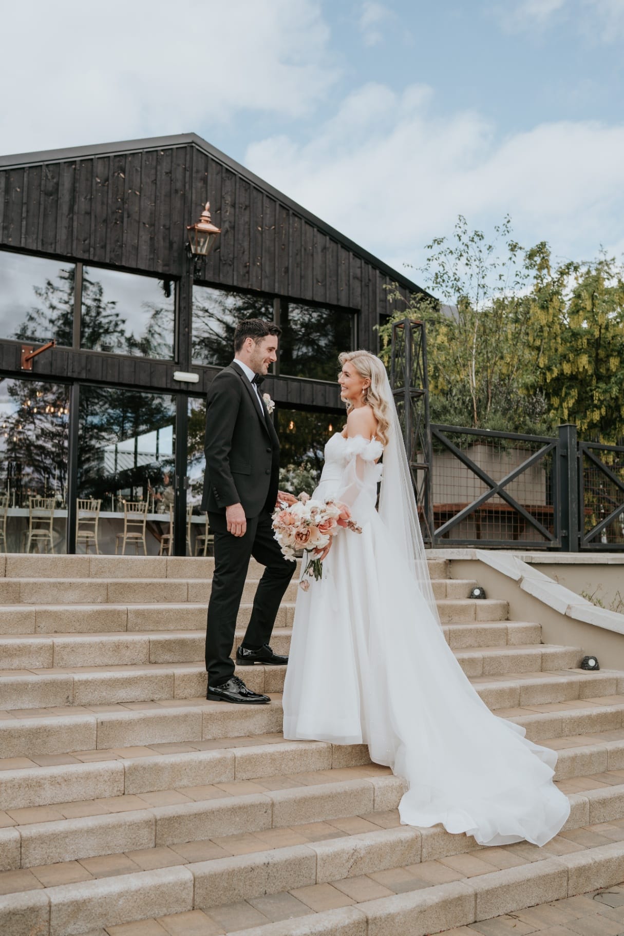 Bride and groom on the stone steps outside The Barn