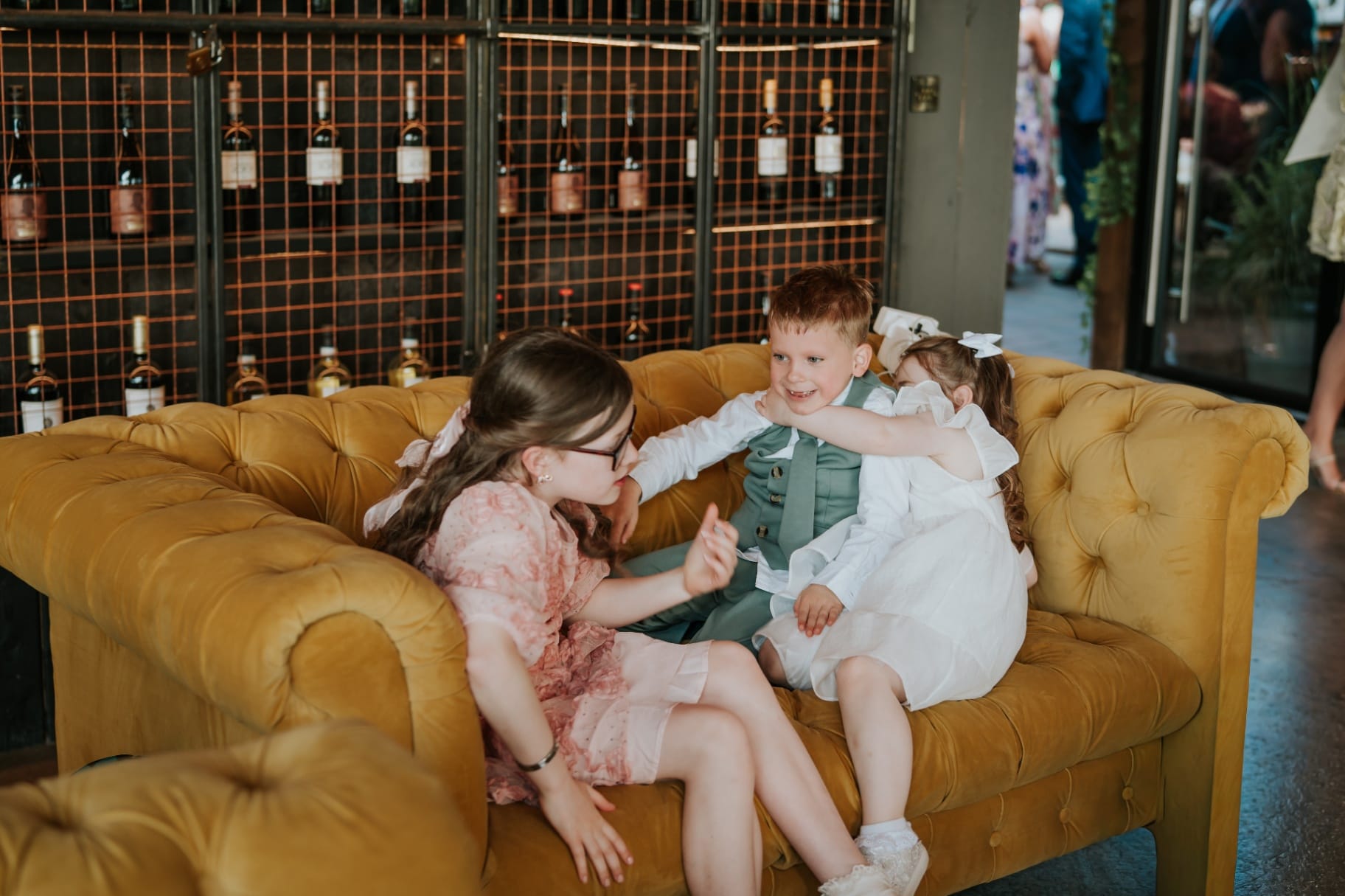 Children playing on a mustard velvet sofa at the Ballyness wedding