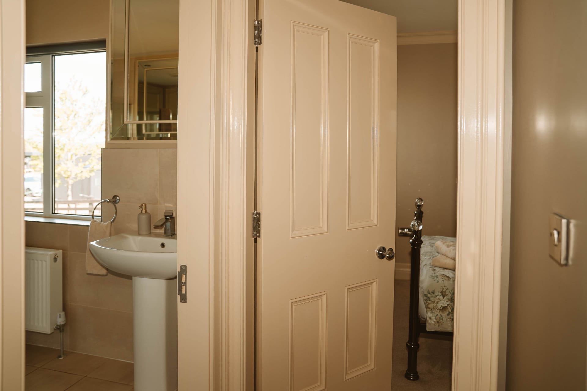 Farmhouse ensuite doorway with basin and bedroom beyond