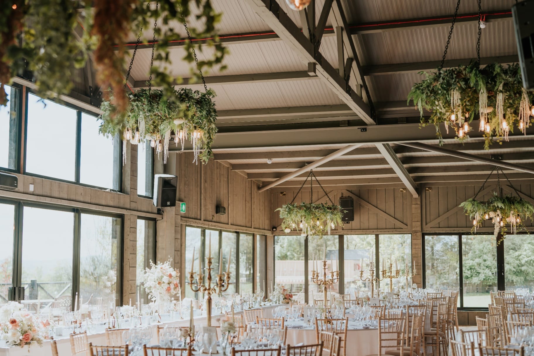 The Barn reception space with hanging floral chandeliers and candlelit tables