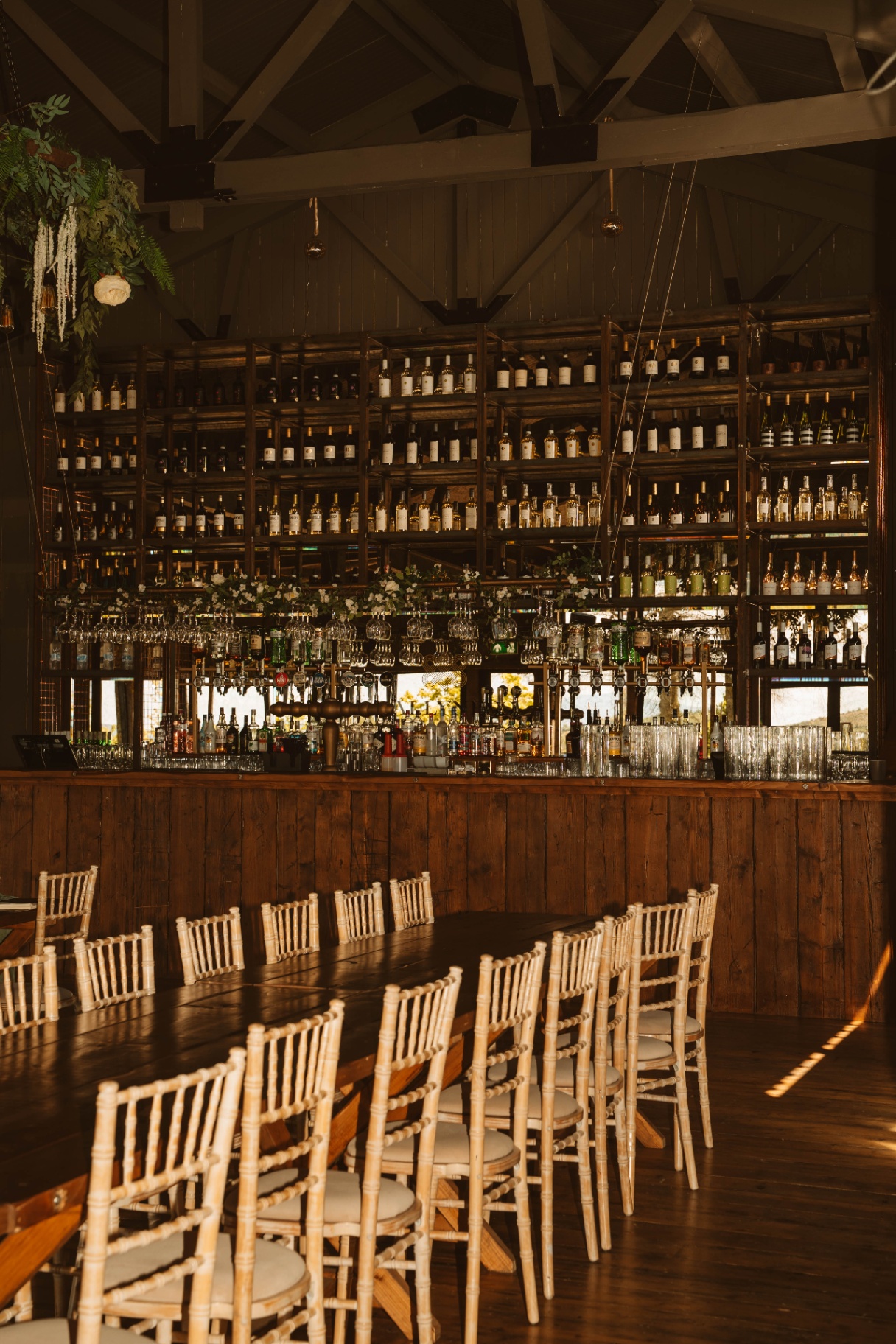 The Stable bar with hanging glassware, floral garlands and pitched white ceiling