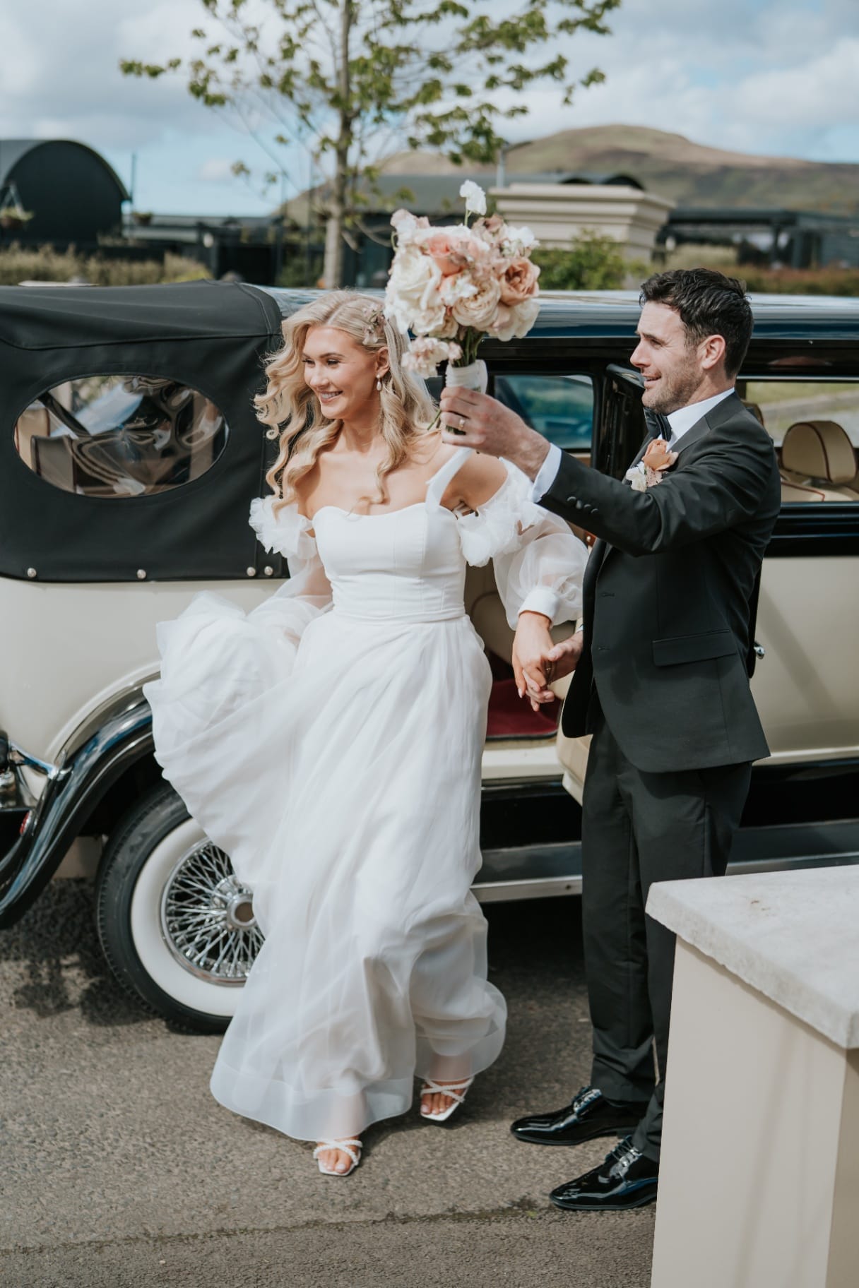 Bride and groom stepping from the vintage wedding car