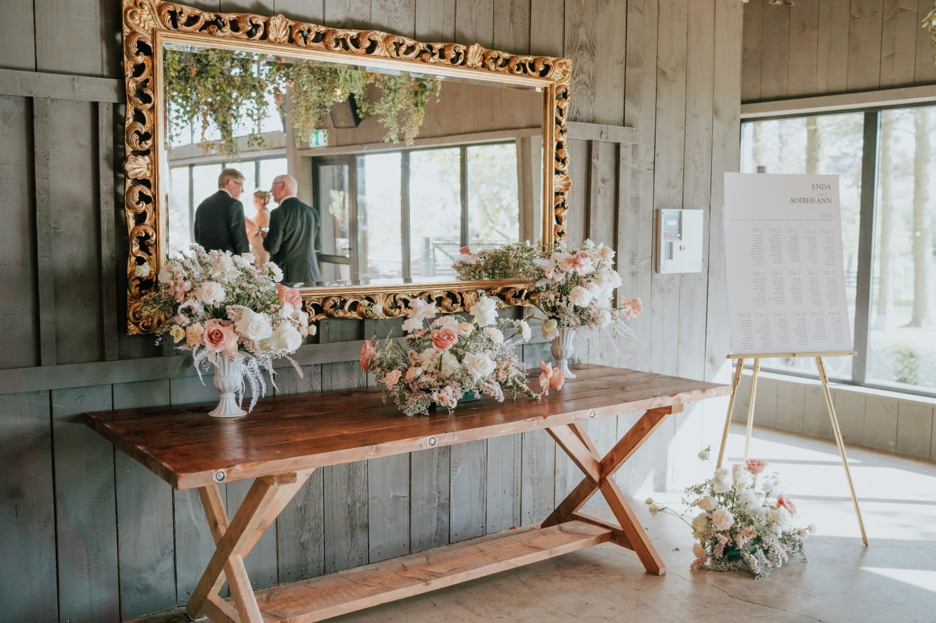 Styled welcome table with ornate mirror and blush floral arrangements at Ballyness