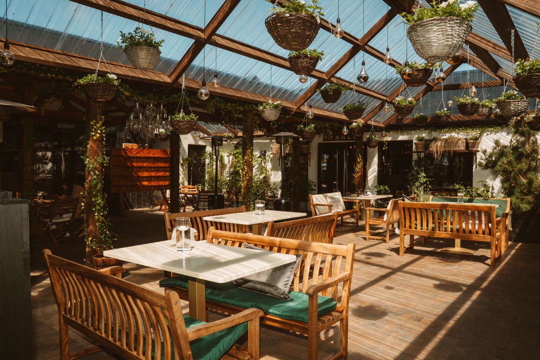 Sunlit conservatory dining beneath hanging baskets