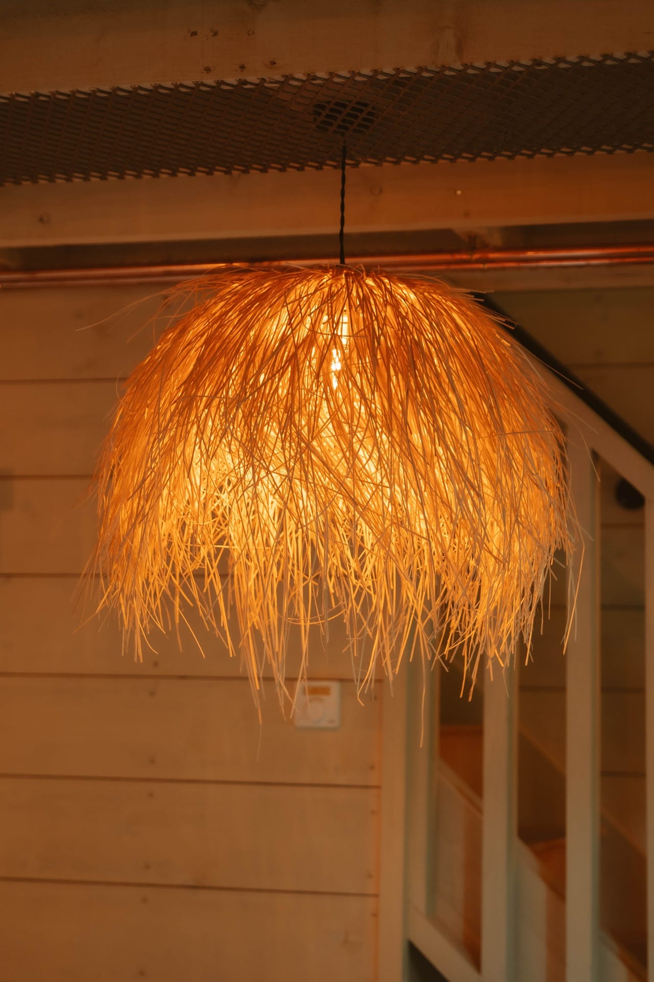 Treehouse Lookout raffia pendant light hanging from copper-lined ceiling