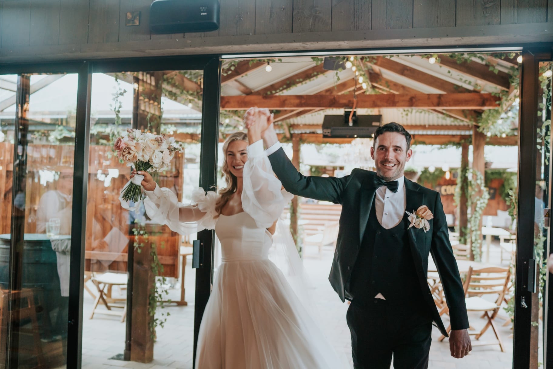 Bride and groom entering the reception with hands raised in celebration