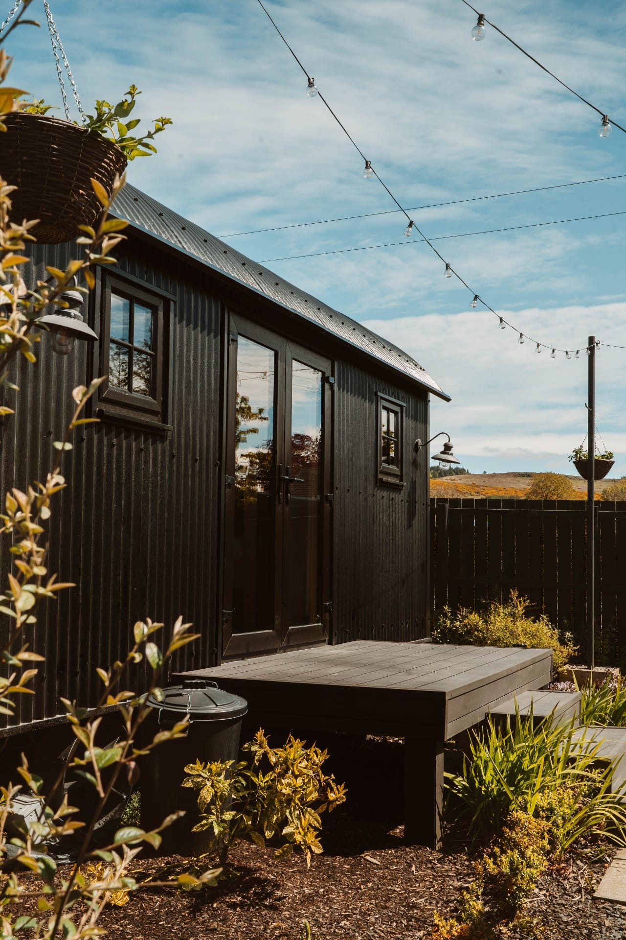 Black Shepherd's Hut exterior with private deck and string lights
