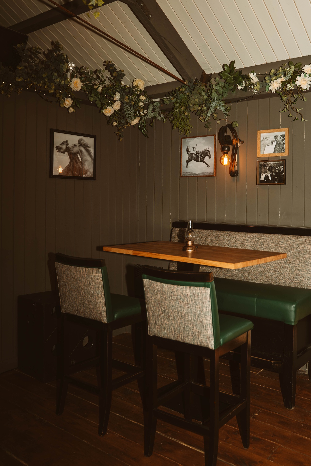 Cosy booth in the Tack Room with green leather seating and horse portraits