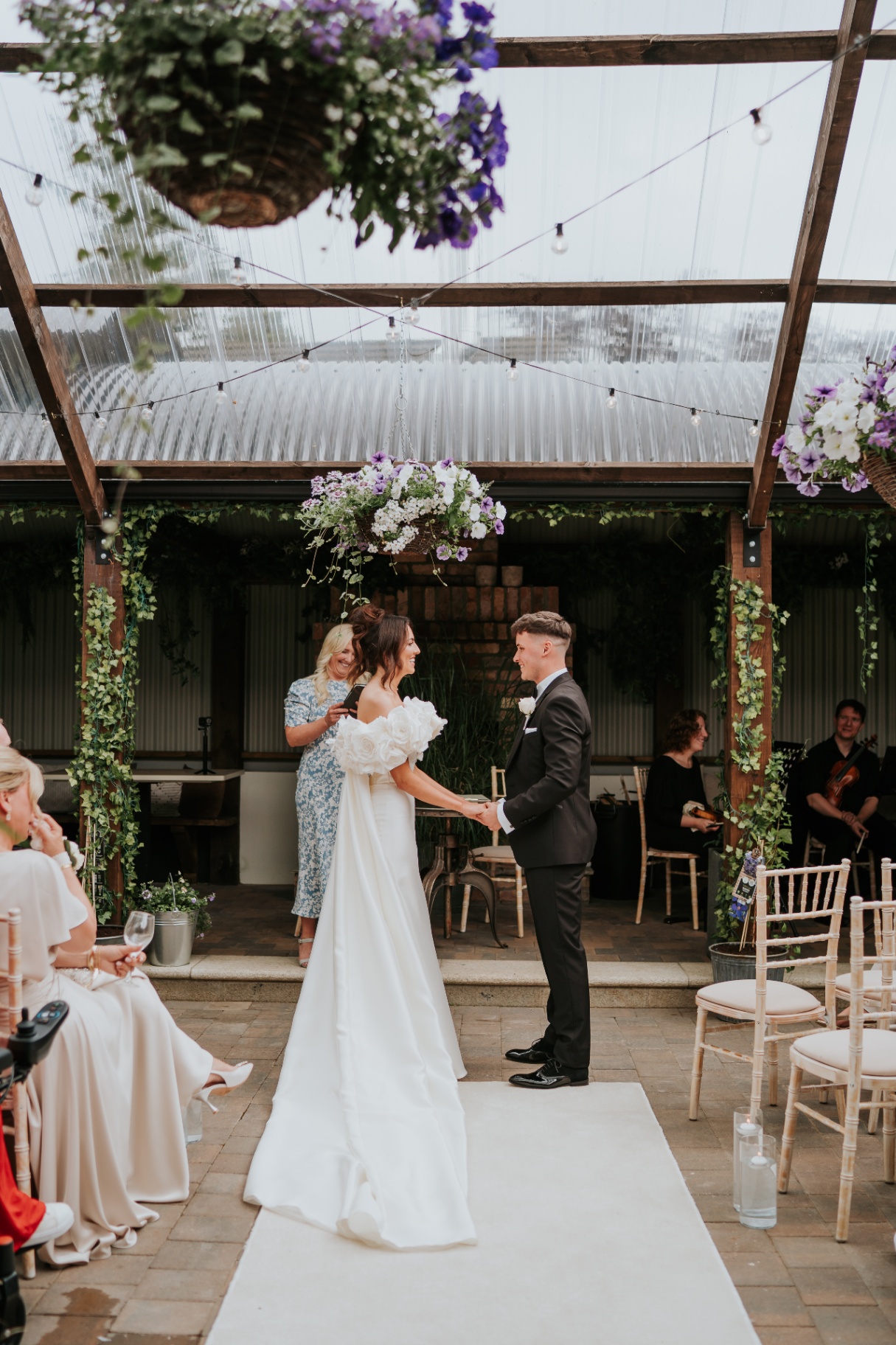 Bride and groom exchanging vows beneath hanging florals