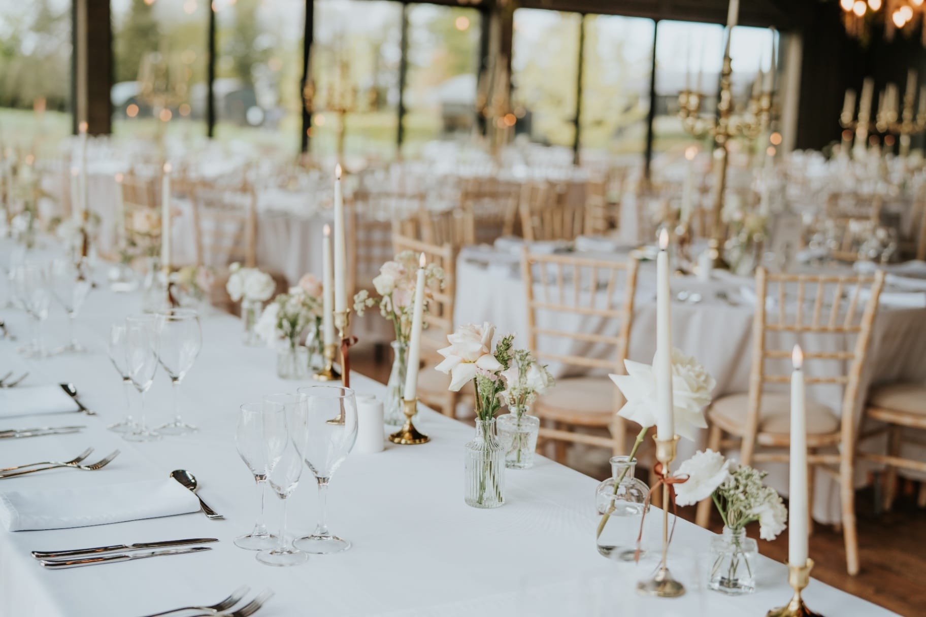 Long top table with bud vases and candles overlooking the gardens