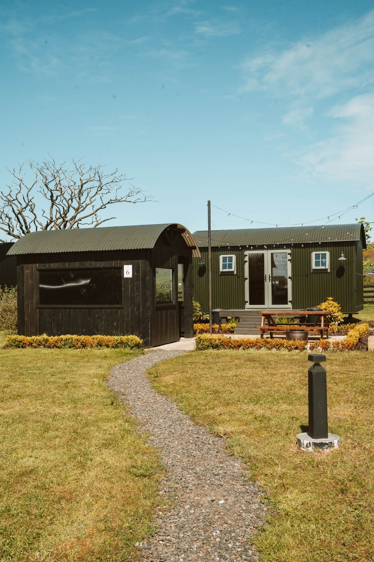 Two Shepherd's Huts side by side with gravel path through the lawn