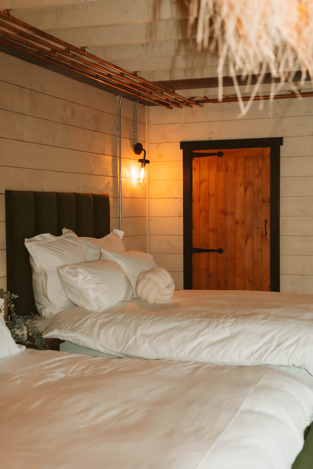 Treehouse Lookout bed with white linen and rustic timber door