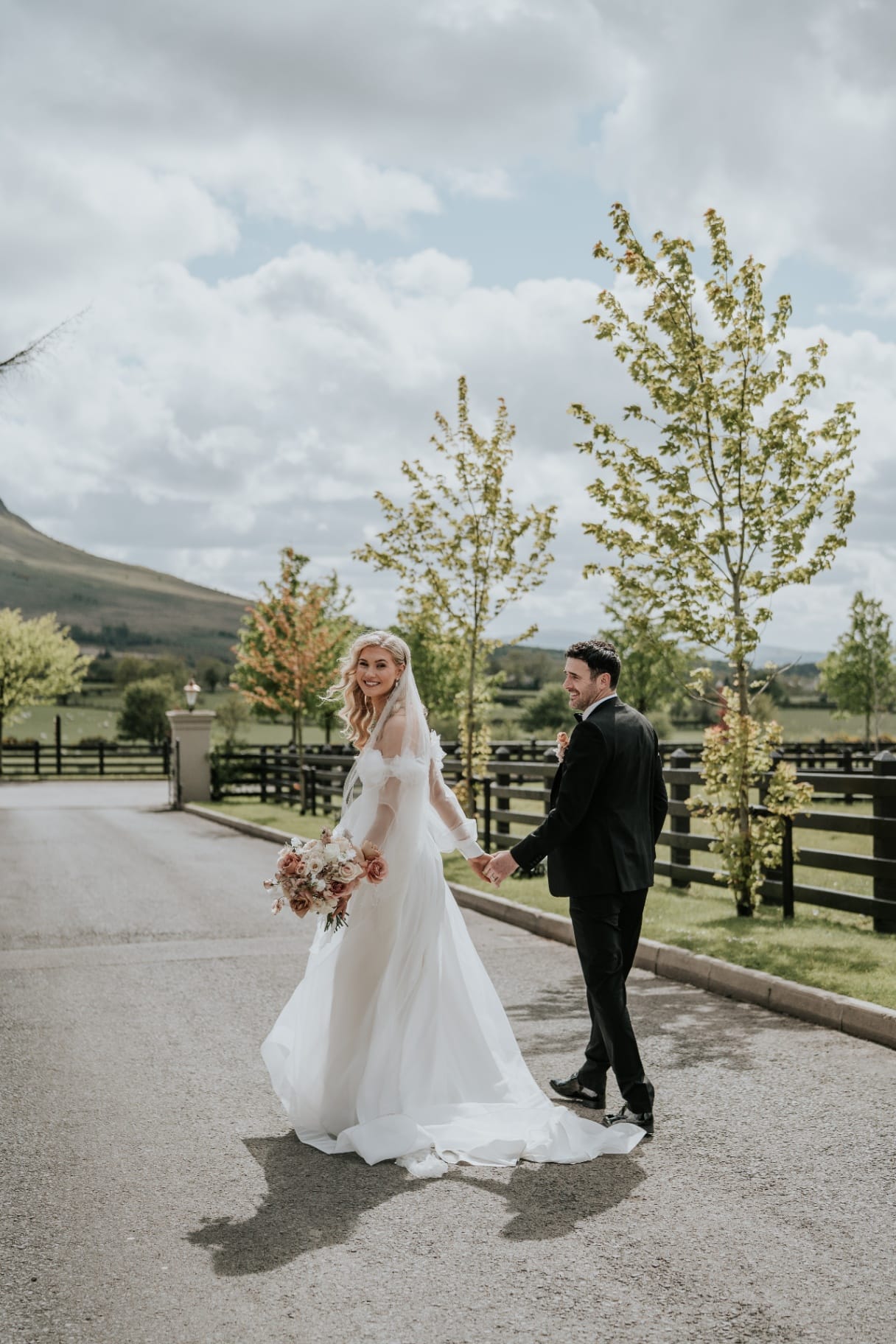 Bride and groom walking hand in hand on the Ballyness driveway