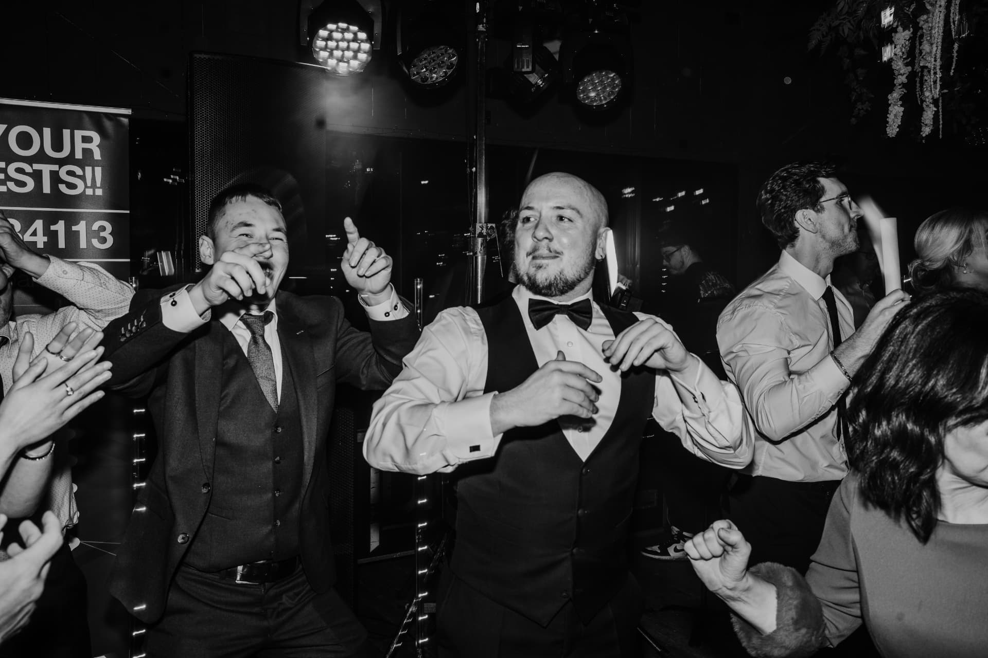 Black and white photograph of guests dancing beneath the lights