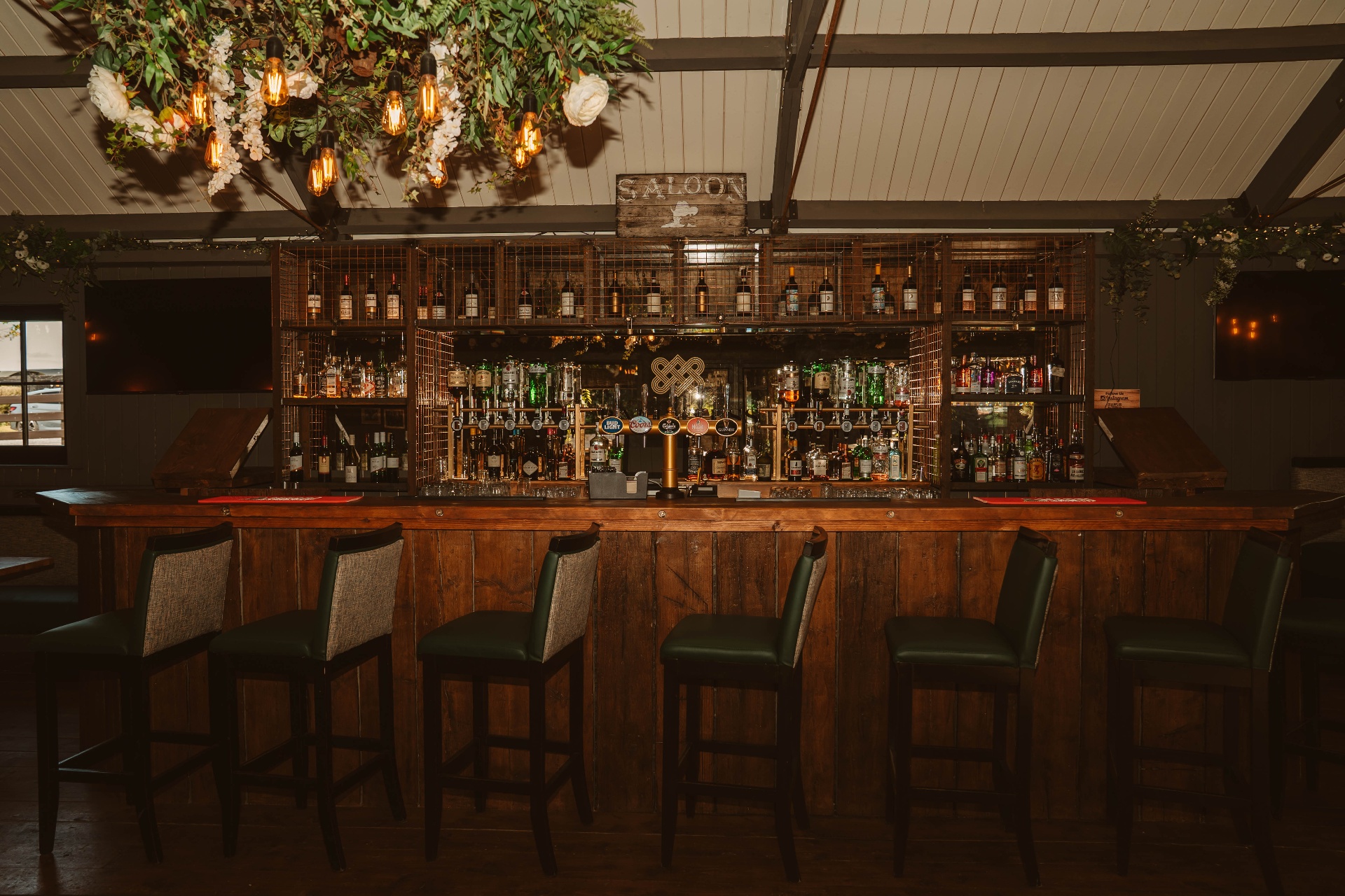 The Saloon bar with cage-fronted whiskey display and hanging Edison bulbs
