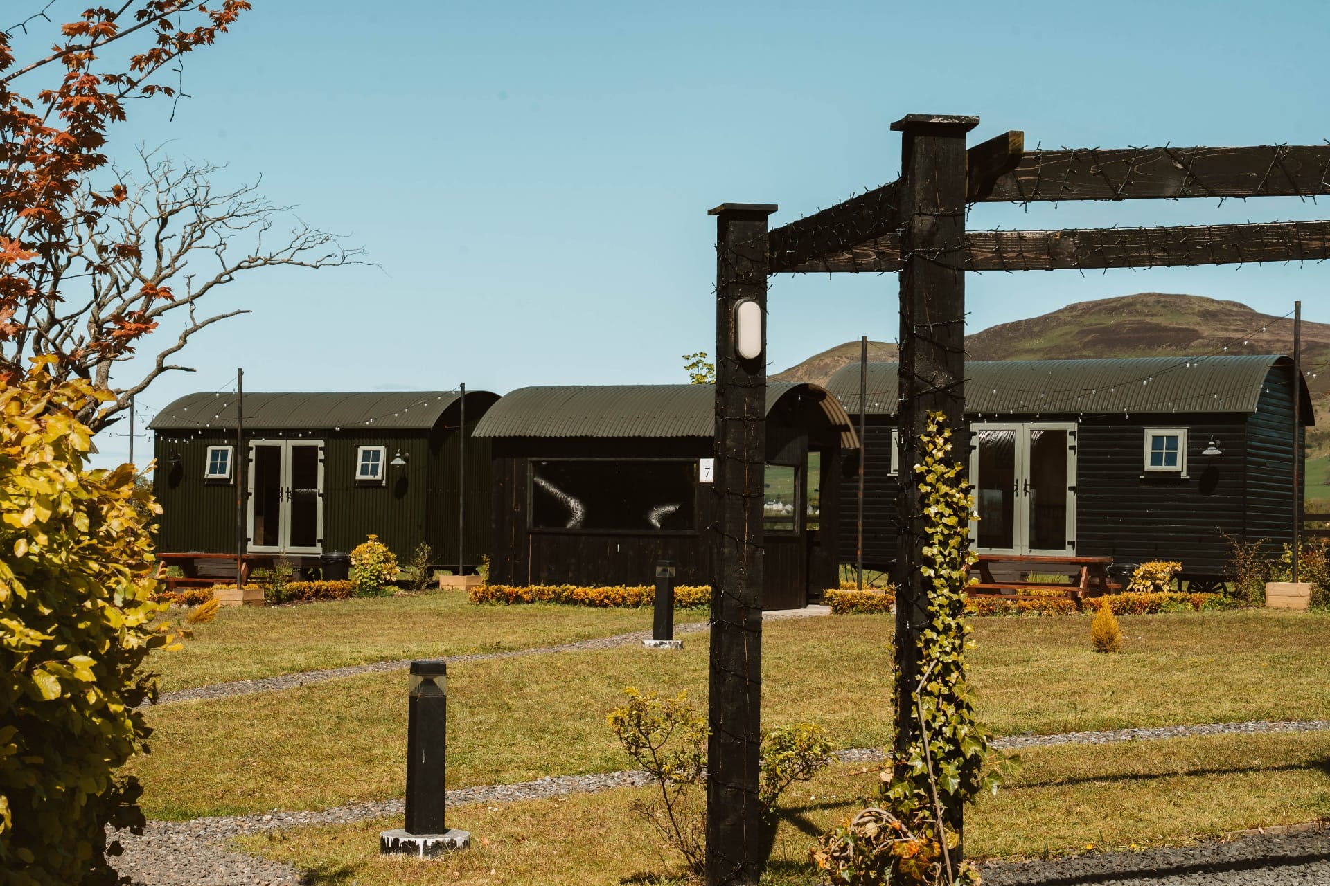 Shepherd's Huts row with mountain backdrop and pergola
