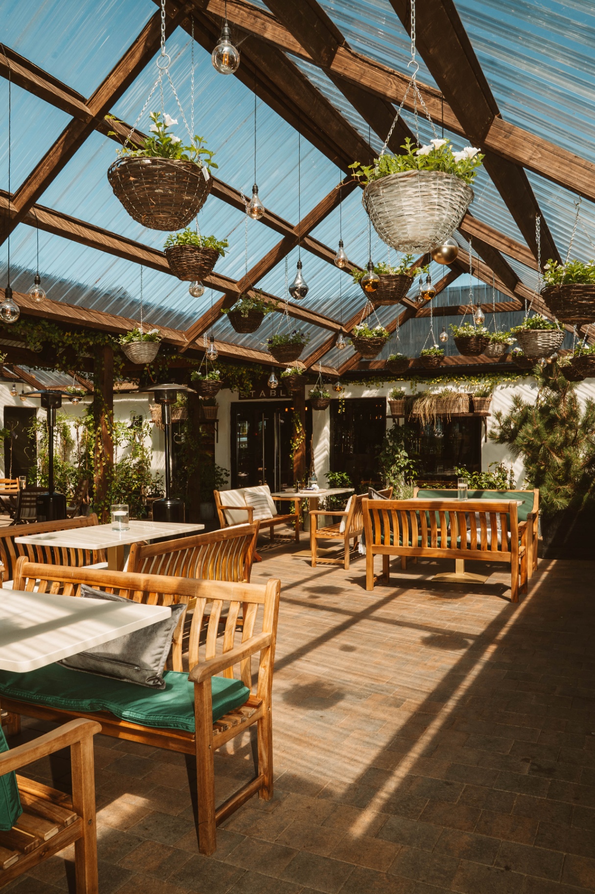 Wide sunlit view across the full Courtyard with hanging baskets and seating