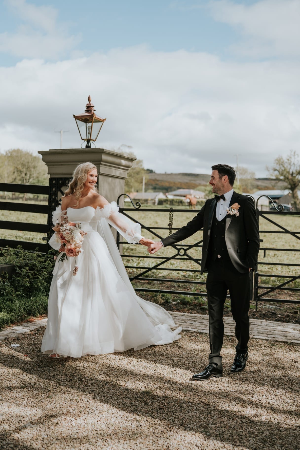 Bride and groom holding hands by the Ballyness entrance gates