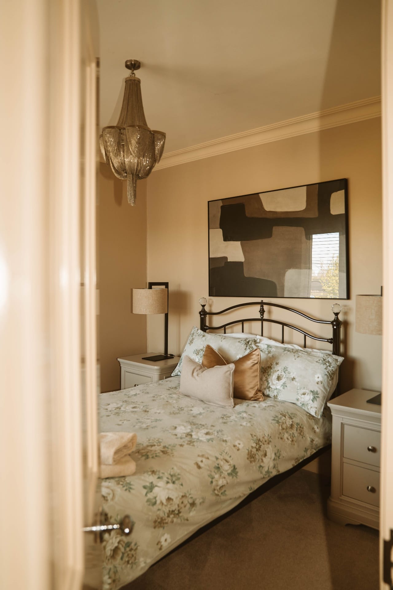 Farmhouse bedroom with chandelier and abstract artwork