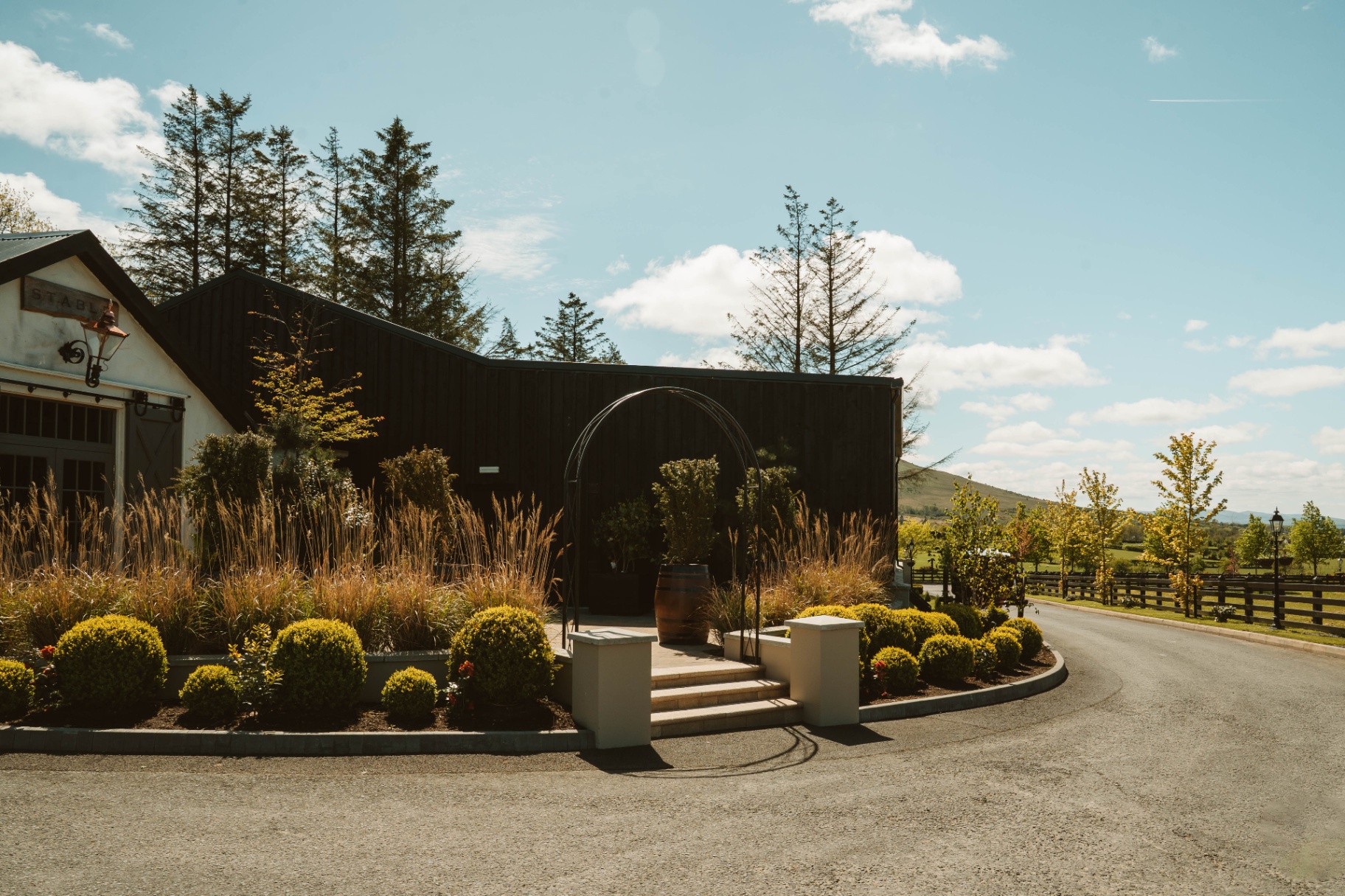 Wide exterior view of the Stable approach with clipped hedging, curved drive and open sky